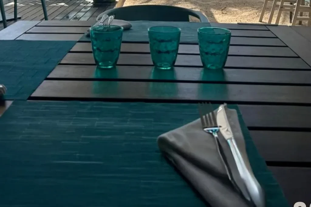 Une table dressée sur la terrasse d'Eden Beach, verres et couverts prêts pour le déjeuner